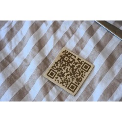 Codigo QR minimalista grabado en madera cuadrada.