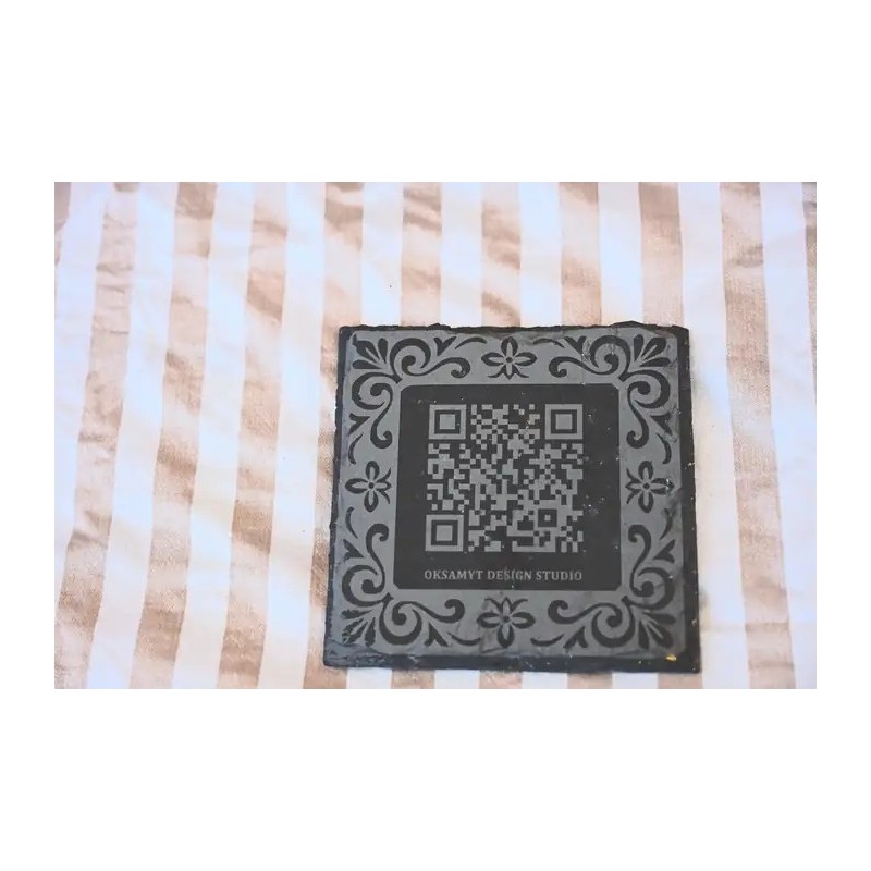 Posavasos corporativo premium en pizarra natural con marco ornamental y codigo QR.